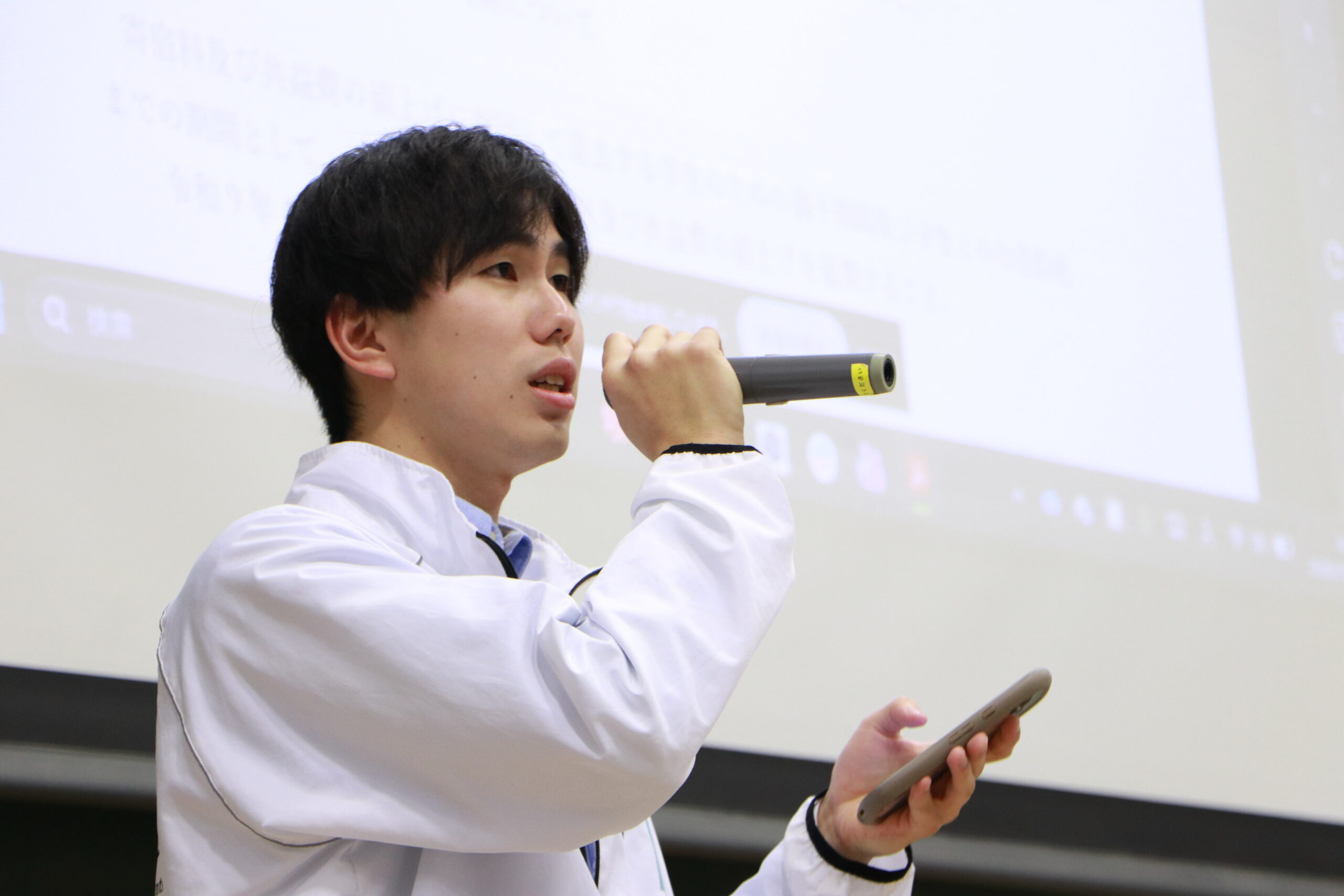 2026年1月7日、3A204教室において行われた令和7年度第8回本会議において、「令和8年度4月1日実施の寄宿料等値上げに関する要請」に関して説明を行う中村文哉生活環境委員会委員長。澁谷耕大撮影。